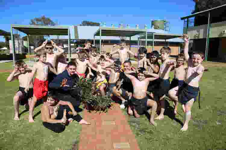The boys Aboriginal Dance Group with two staff members, dressed in traditional lap laps and ochre paint. Students and staff posing in traditional style.