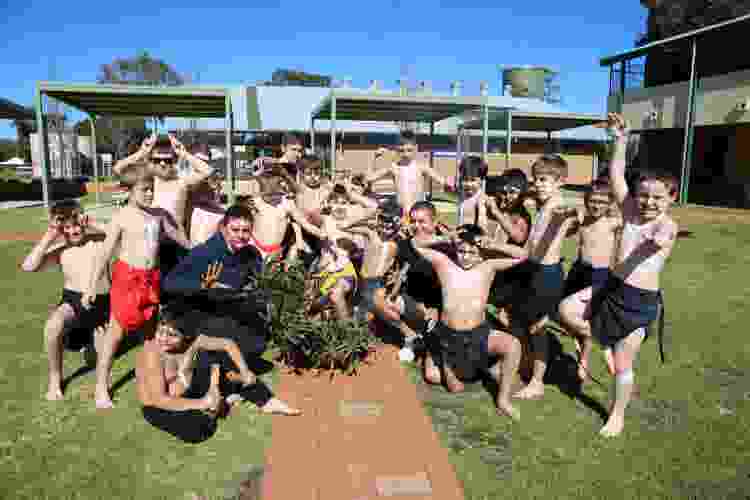 Students and 2 adults in traditional poses facing the camera, dressed in traditional outfits
