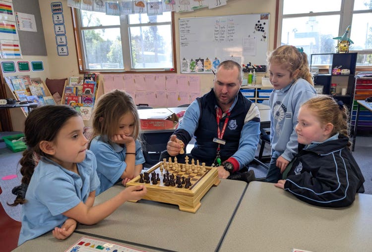 Teacher teaching studnets about Chess, set in a classroom