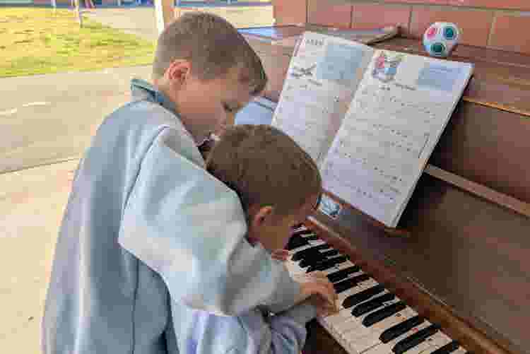 One students helping another to play our playground piano.