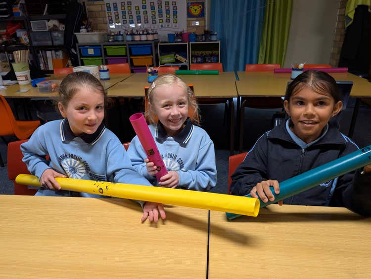 3 students playing with Boomwhacker musical instruments