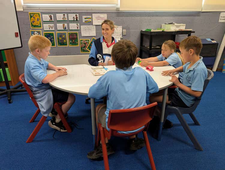 4 students sitting with a staff person at a table for learning
