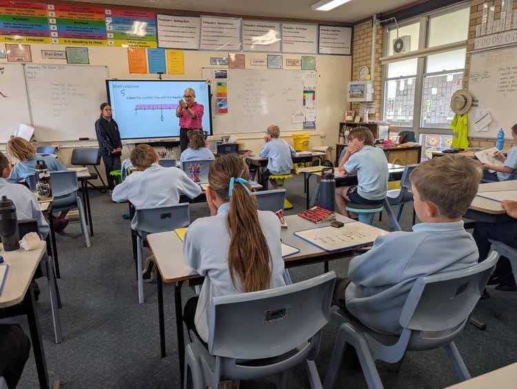 Teacher and student in the background leading the class through a fractions lesson