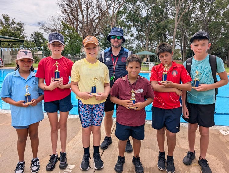 Six students received their age champion trophies at the swimming carnival. The pool is in the background.